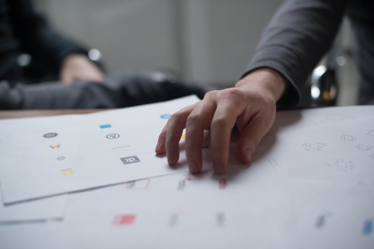 services-01 A close-up shot of a hand reviewing various logo designs on paper, ideal for business concepts.