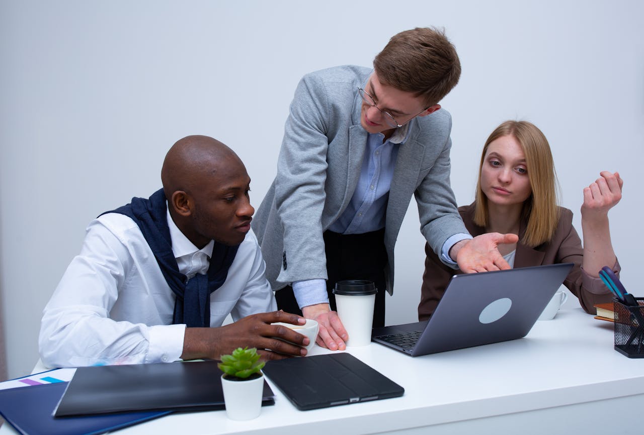 team-02 Three professionals engage in a lively business discussion at a modern office desk, focusing on teamwork.